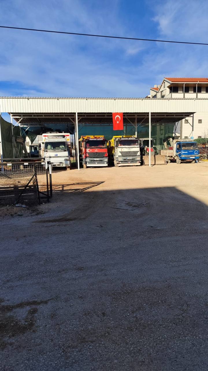 Çatılı alanda park halinde damperli kamyonlar ve iş makineleri
