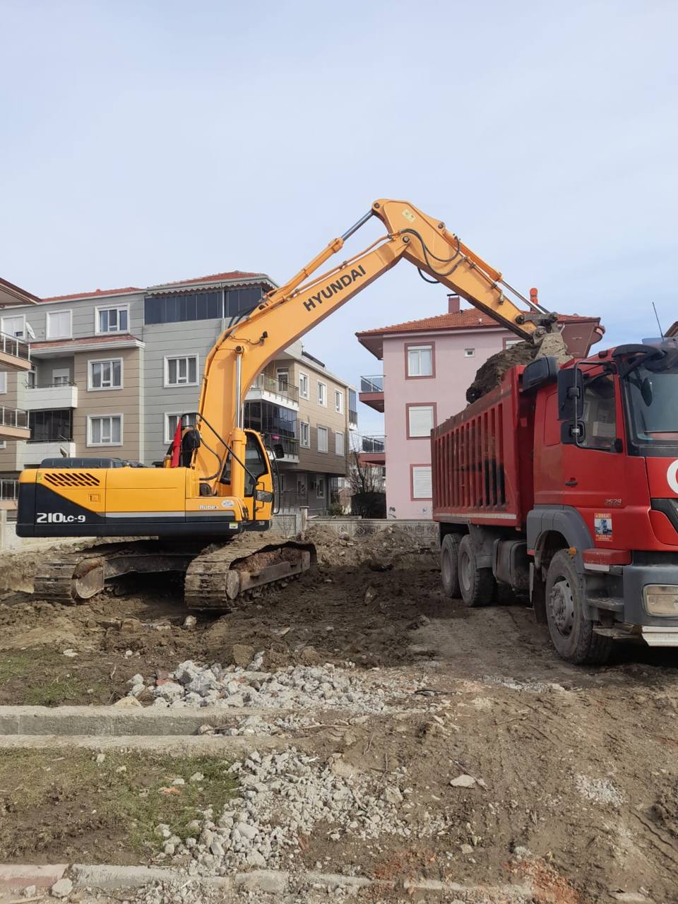 Mahalle içinde ekskavatör kamyona toprak yüklüyor